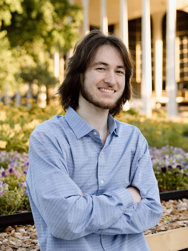 Zachariah Jones smiling with arms crossed on the Oral Roberts University campus